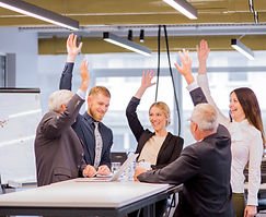 Five business colleagues raising hands, celebrating success in a modern office.