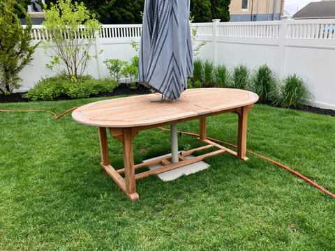 Oval wooden outdoor dining table with closed umbrella on green lawn. Snow removal near me | Down To Earth Landscaping | Residential landscaping near me| Down To Earth Landscaping | Jackson New Jersey, USA (732) 833-7702