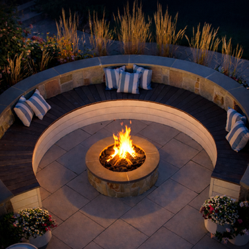 Circular patio fire pit, built-in seating with cushions at night.