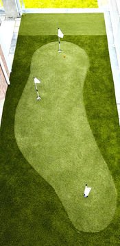 Lush green artificial putting green with three golf flags for practice.