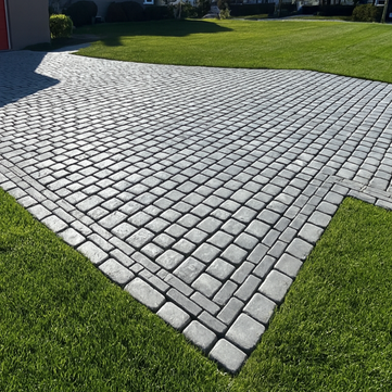 Grey interlocking paver driveway with green grass on a sunny day. Residential landscaping near me| Down To Earth Landscaping | Jackson New Jersey, USA (732) 833-7702