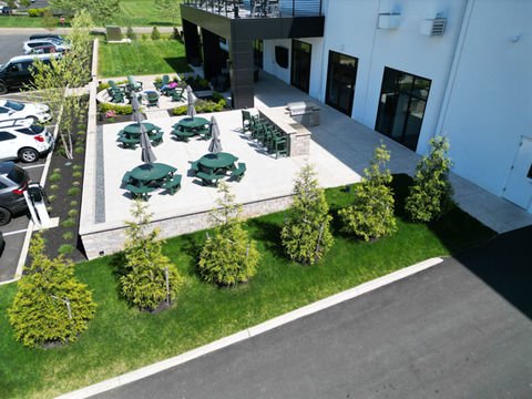 Outdoor patio, green picnic tables, umbrellas, modern building. Commercial Portfolio. | Down To Earth Landscaping | Jackson New Jersey, USA (732) 833-7702
