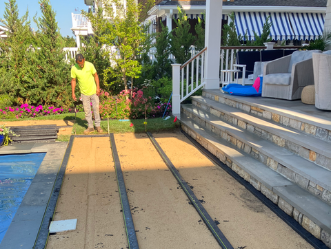 Landscaper installing artificial grass by a luxurious pool and patio. Residential landscaping near me| Down To Earth Landscaping | Jackson New Jersey, USA (732) 833-7702