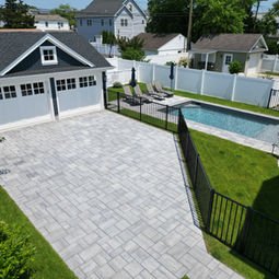 Modern two-car garage, spacious paved driveway, and backyard swimming pool.