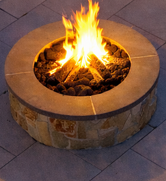 Circular stone fire pit glowing with warm flames on patio. Residential landscaping near me| Down To Earth Landscaping | Jackson New Jersey, USA (732) 833-7702