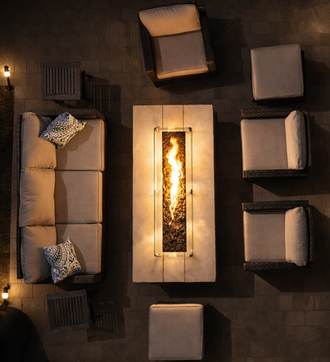 Modern outdoor patio furniture arrangement around a glowing fire pit at night.