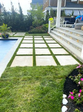 Backyard with square stepping stones, lush grass, poolside patio, and house. Residential landscaping near me| Down To Earth Landscaping | Jackson New Jersey, USA (732) 833-7702
