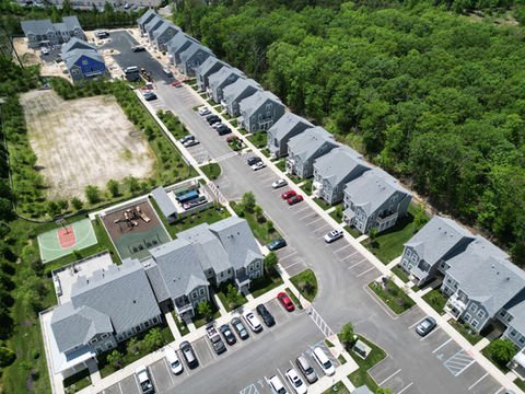 Aerial view: numerous residential townhouses, playground, tennis court, and surrounding forest. | Down To Earth Landscaping | Jackson New Jersey, USA (732) 833-7702