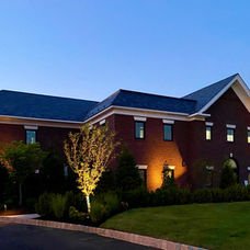 Large brick building with dark blue roof, outdoor lighting, green lawn. | Down To Earth Landscaping | Jackson New Jersey, USA (732) 833-7702