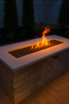 Modern rectangular fire pit with vibrant flames, stone base, dark garden. Residential landscaping near me| Down To Earth Landscaping | Jackson New Jersey, USA (732) 833-7702